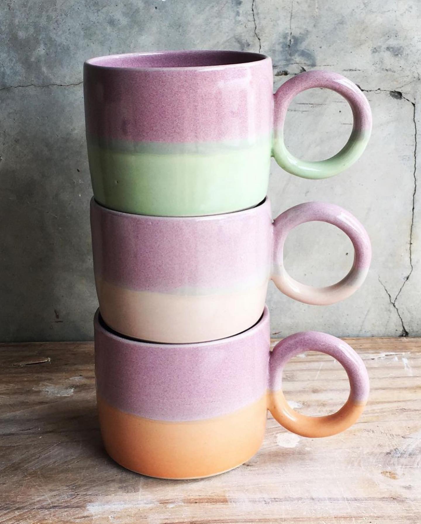 Three mugs are stacked on top of each other on a wooden table.
