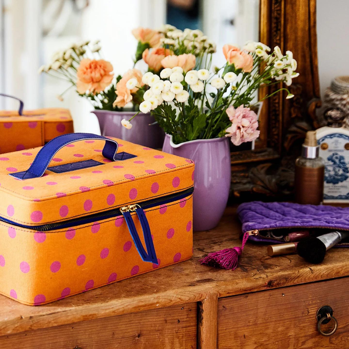 A polka dot vanity case sits on a wooden table