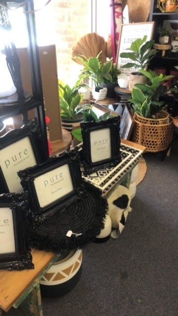 A bunch of picture frames are sitting on a table in a room.