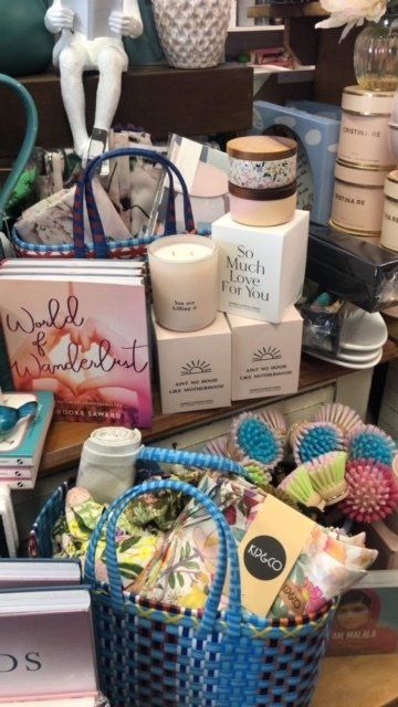 A blue basket filled with books and candles on a table