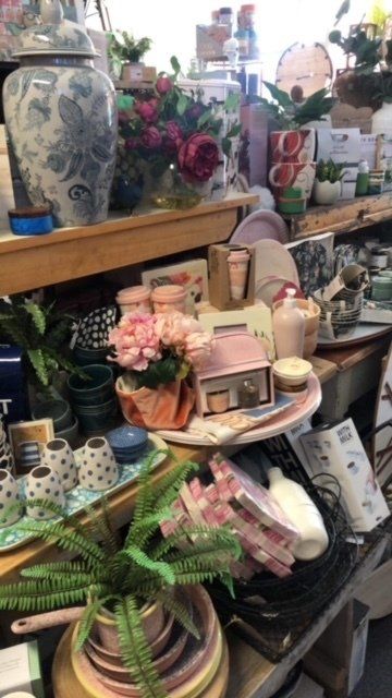 A shelf filled with lots of items including vases and flowers