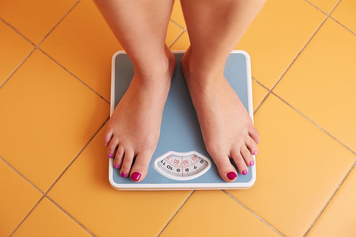 Woman on scale, showing the hidden hormone connection in weight loss - Absolute Wellness