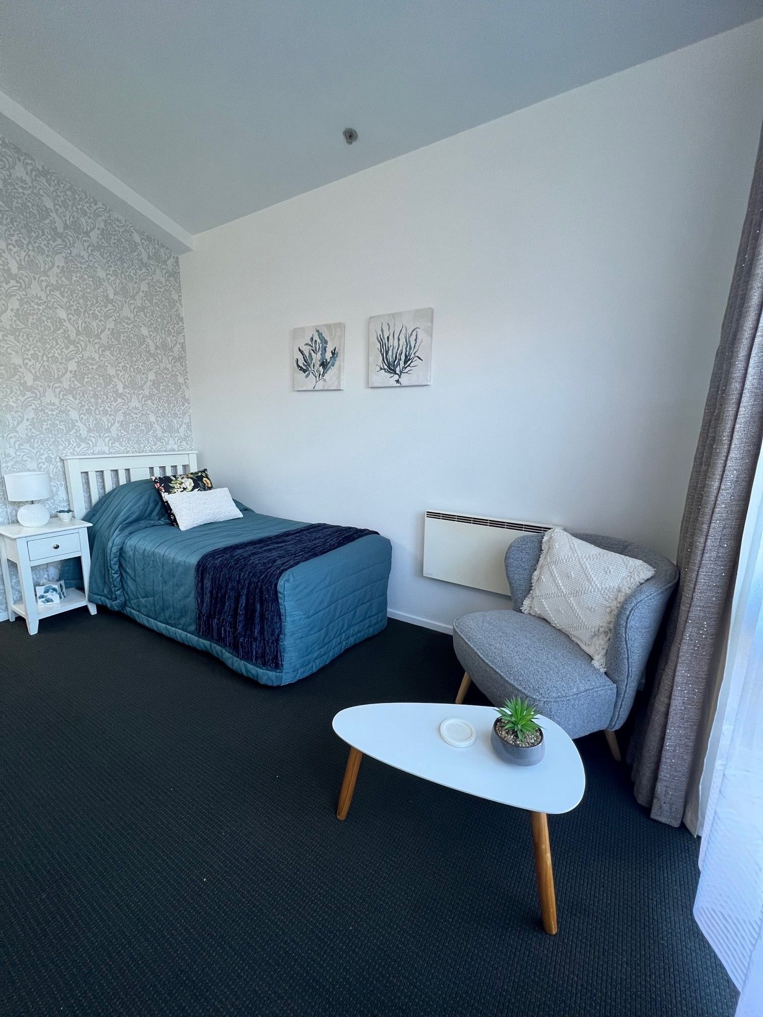 A bedroom with a bed , chair , table and window.