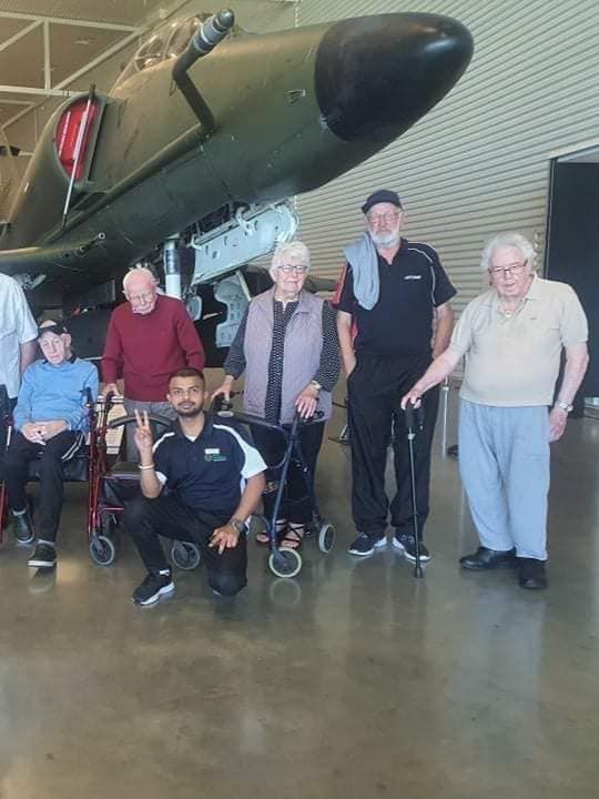 A group of people are posing for a picture in front of a plane.
