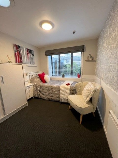 A bedroom with a single bed and a chair