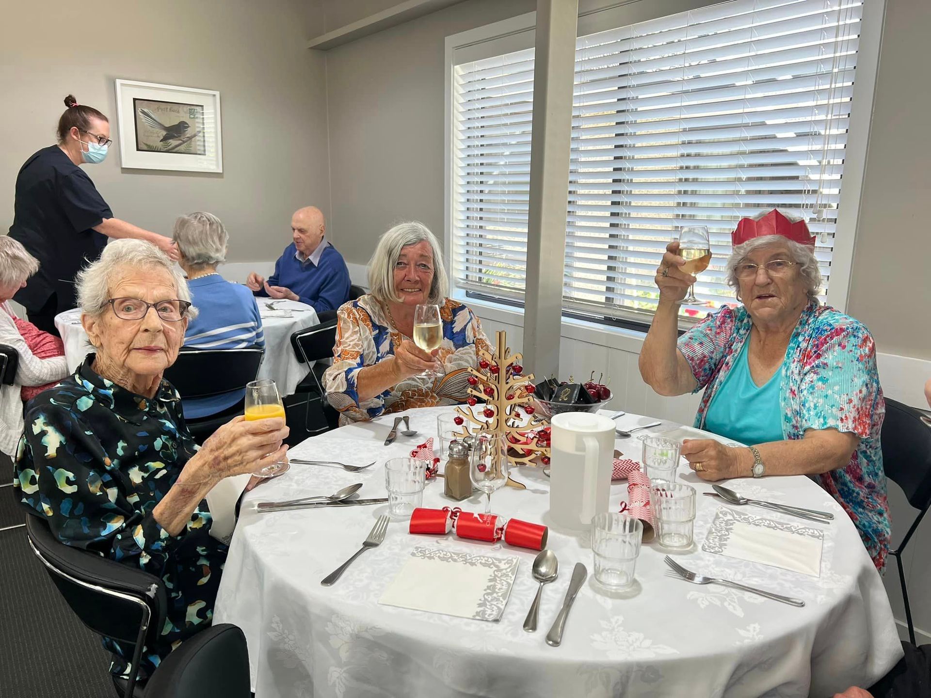 A group of elderly people are sitting at a table toasting with champagne.