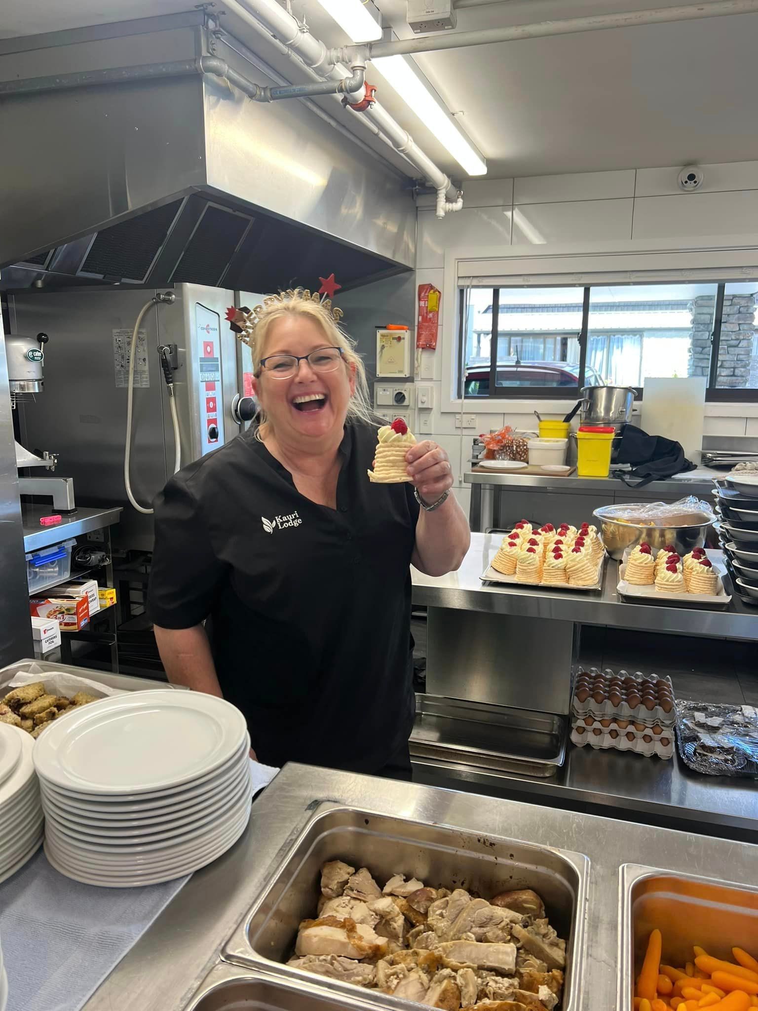 A woman is standing in a kitchen holding a piece of cake.