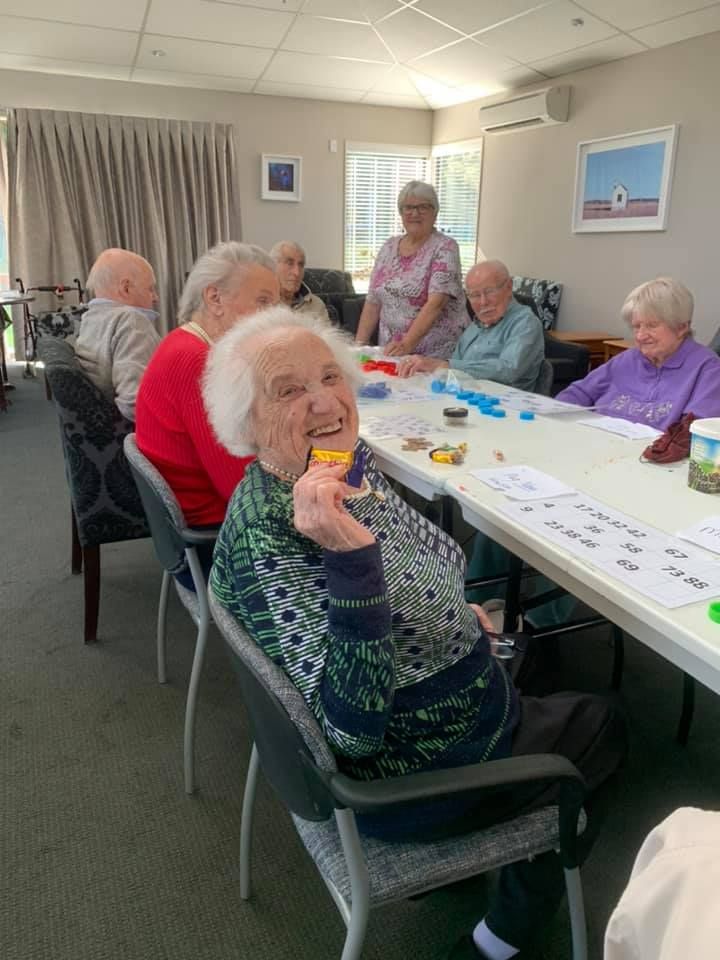 A group of elderly people are sitting around a table in a room.