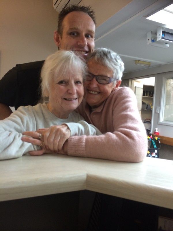 A man and two women are hugging each other on a counter.