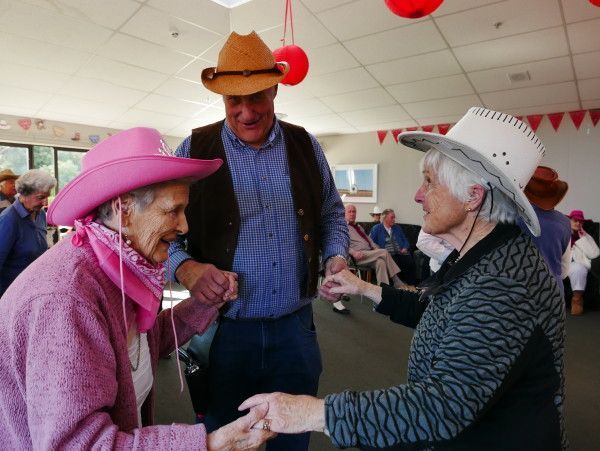 A group of people wearing cowboy hats are dancing in a room.