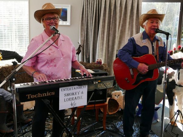 A man is playing a guitar and a woman is playing a keyboard.