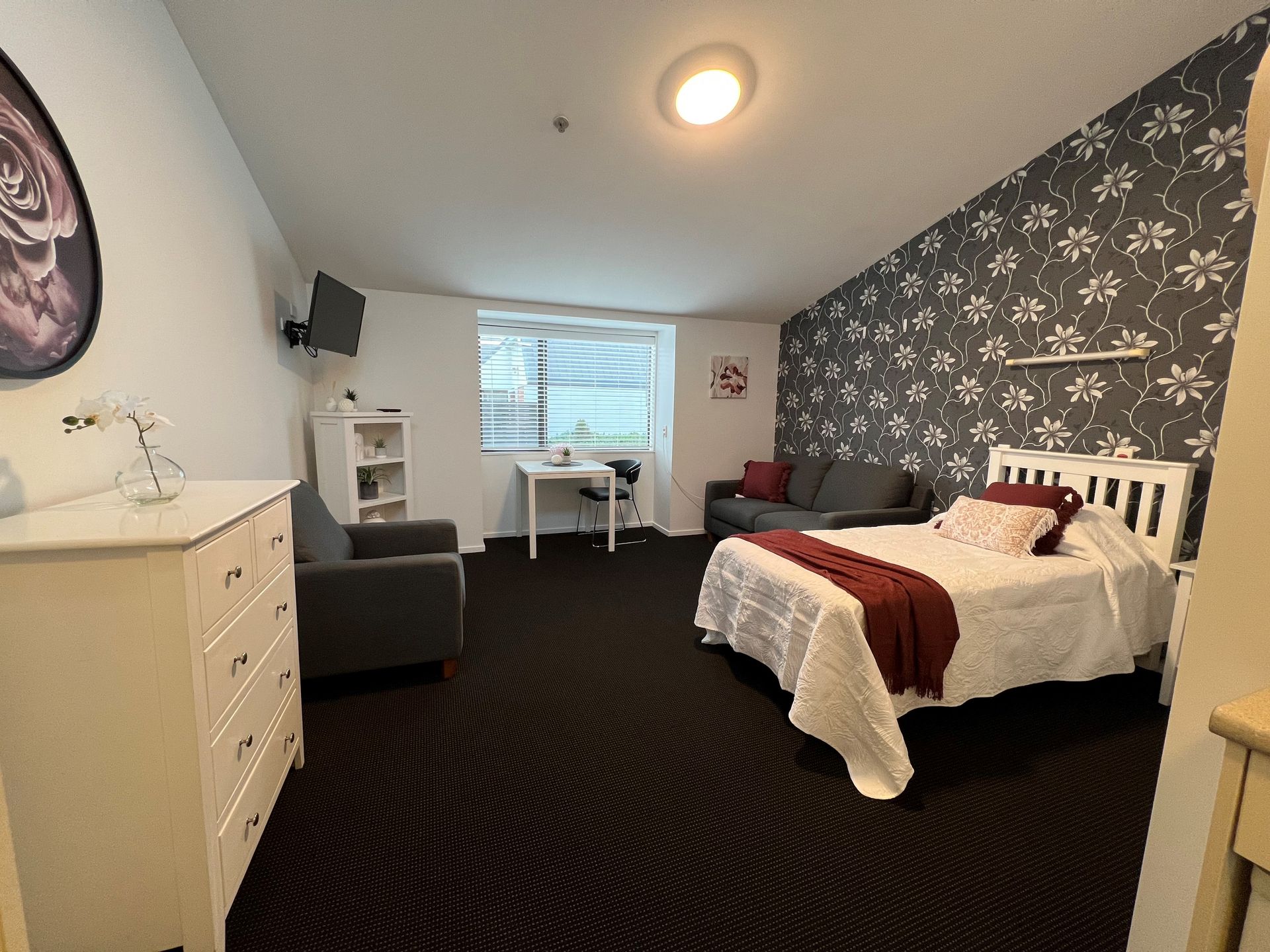A bedroom with a bed , couch , desk and television.