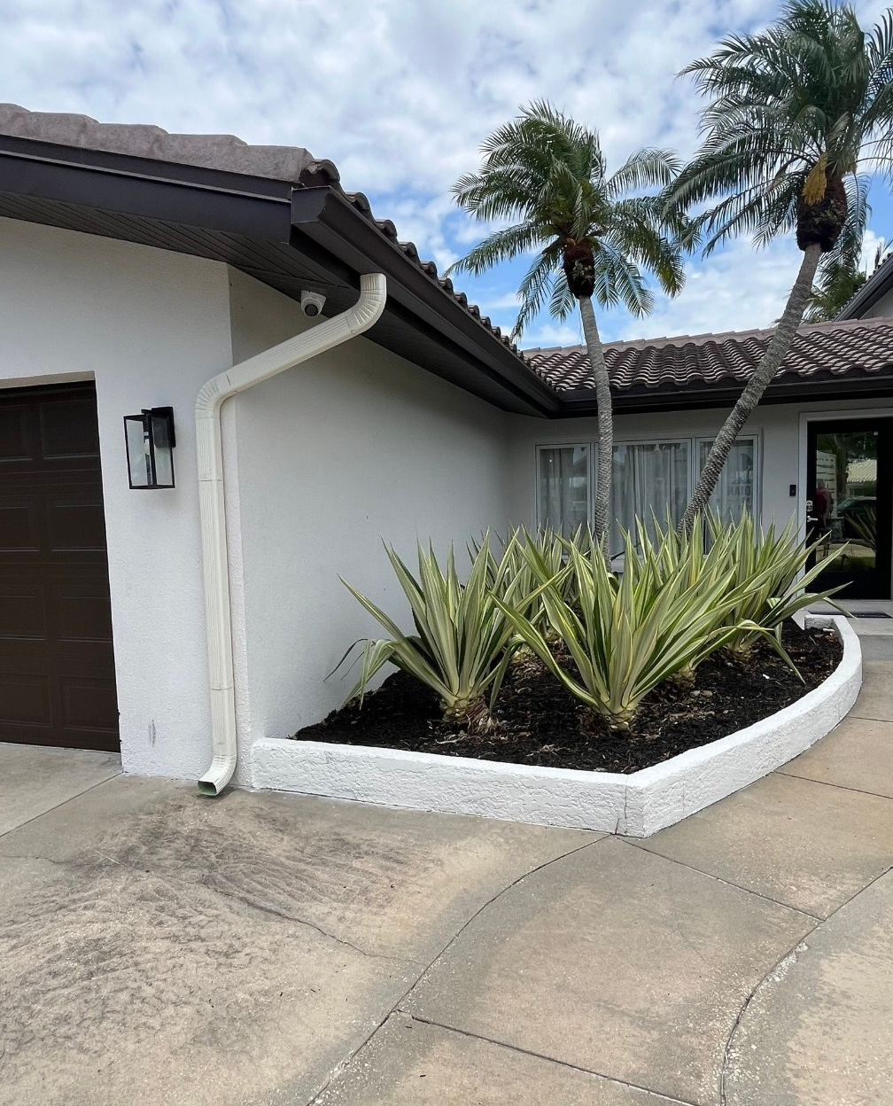 A person is installing a white gutter on a roof.