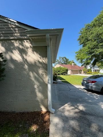 A white house with a white gutter and a blue sky in the background