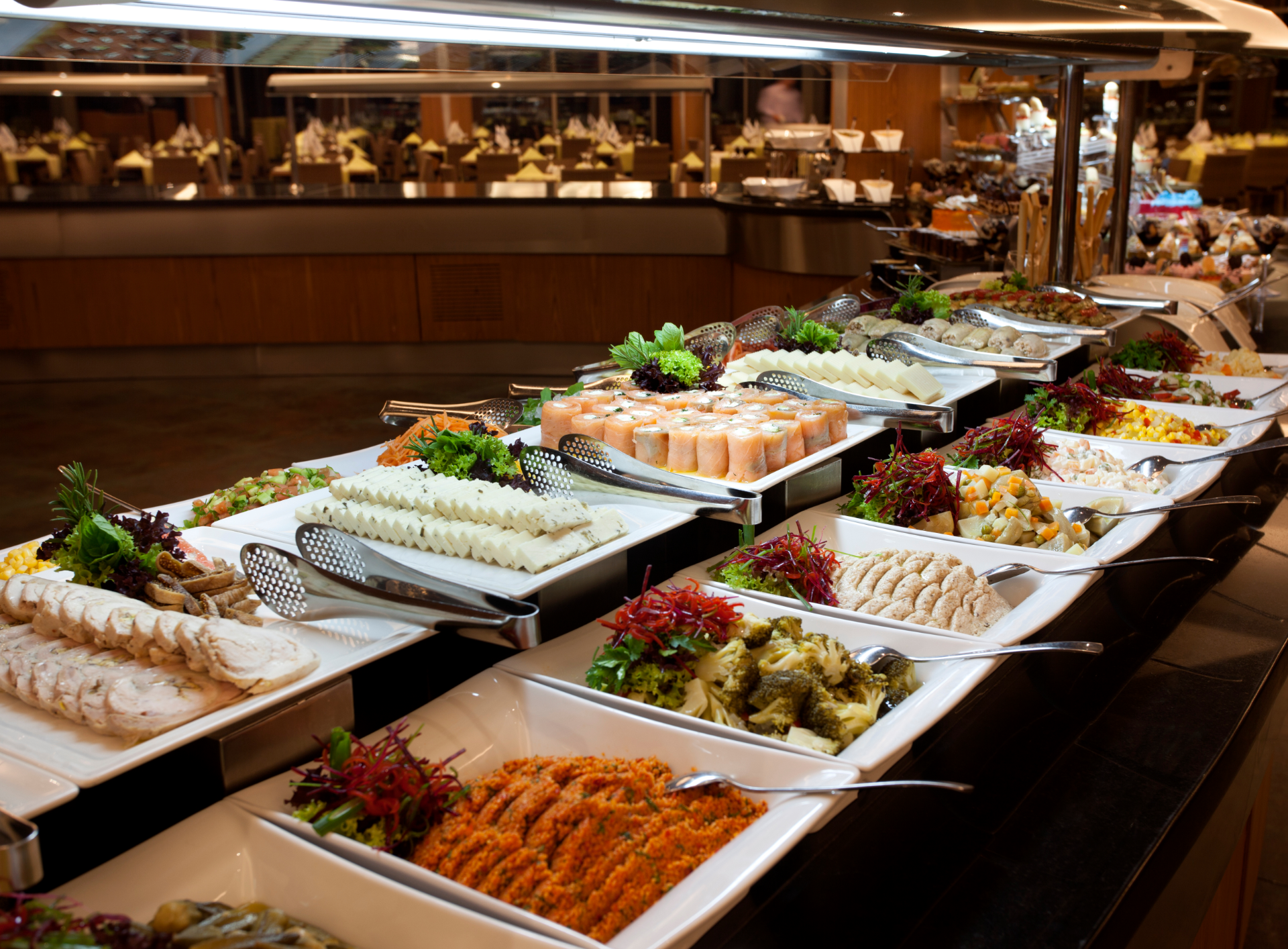 Buffet with various food dishes, brightly lit, indoor setting.