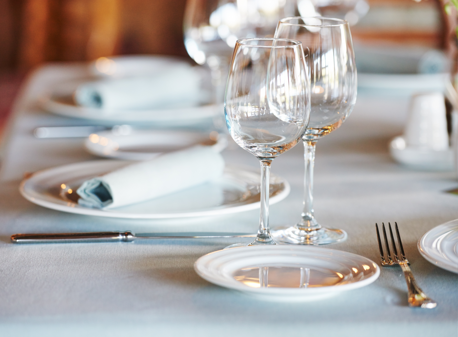 Formal dining table set with plates, silverware, and wine glasses.