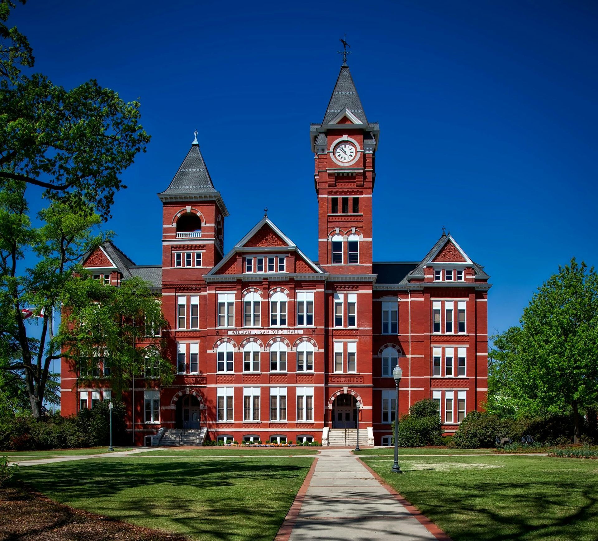Red brick Auburn University building with clock tower and green lawn.