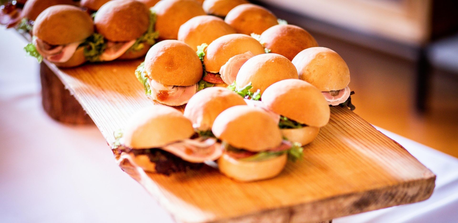 Miniature sandwiches on a wooden serving board, ready to eat.