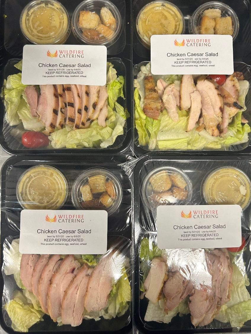Four pre-packaged chicken salads in black containers, each with dressing, croutons, and a label.