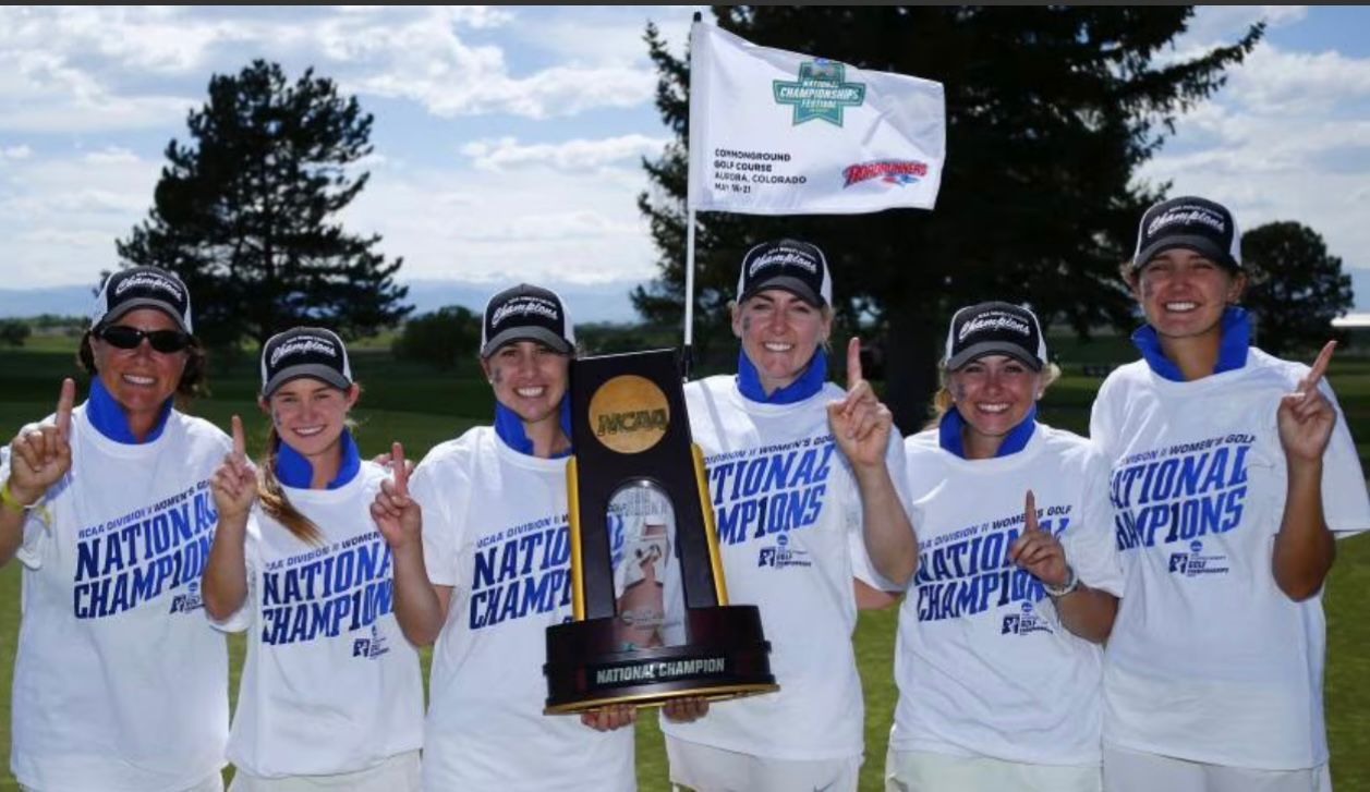 Women's golf team holding trophy, wearing 