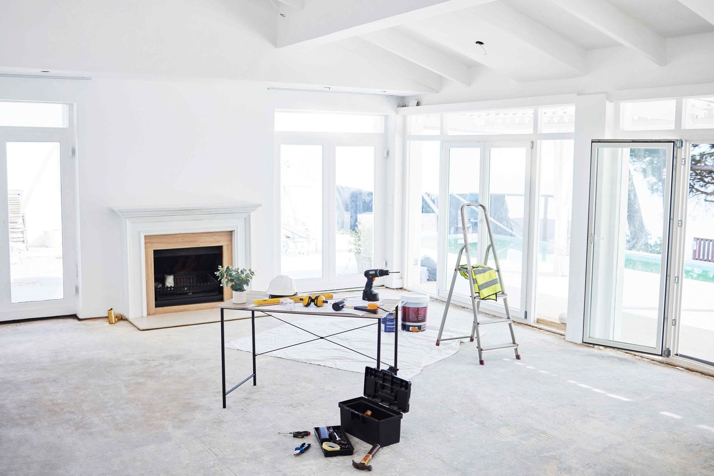 An empty living room with a fireplace and a table with tools on it.
