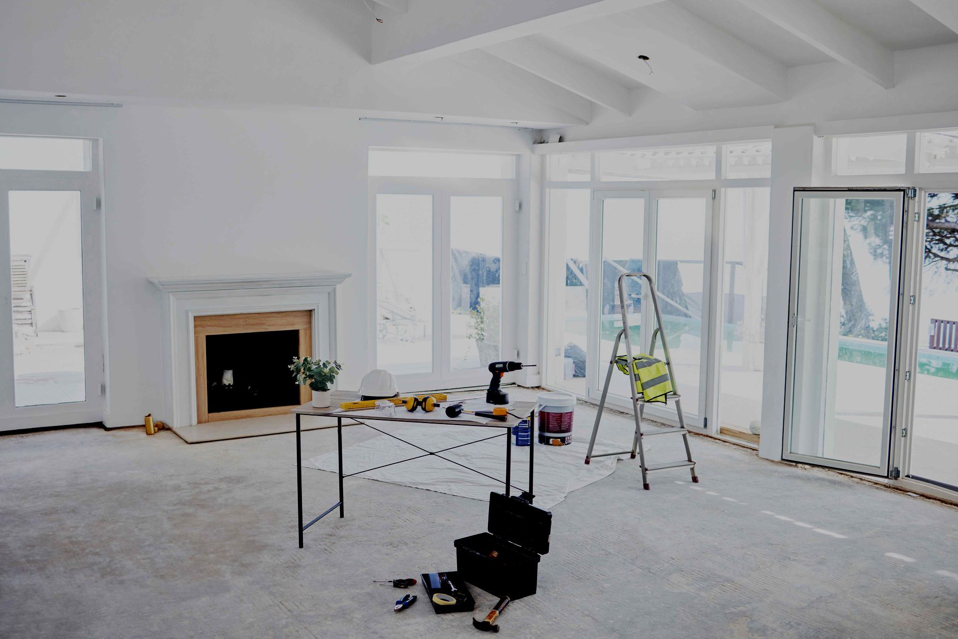 An empty room with a table and a ladder in it.