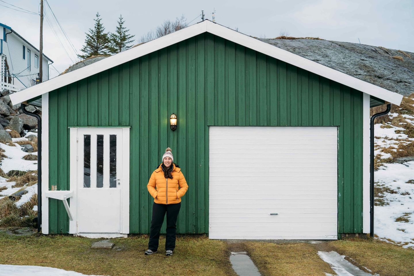 A man is standing in front of a green garage.