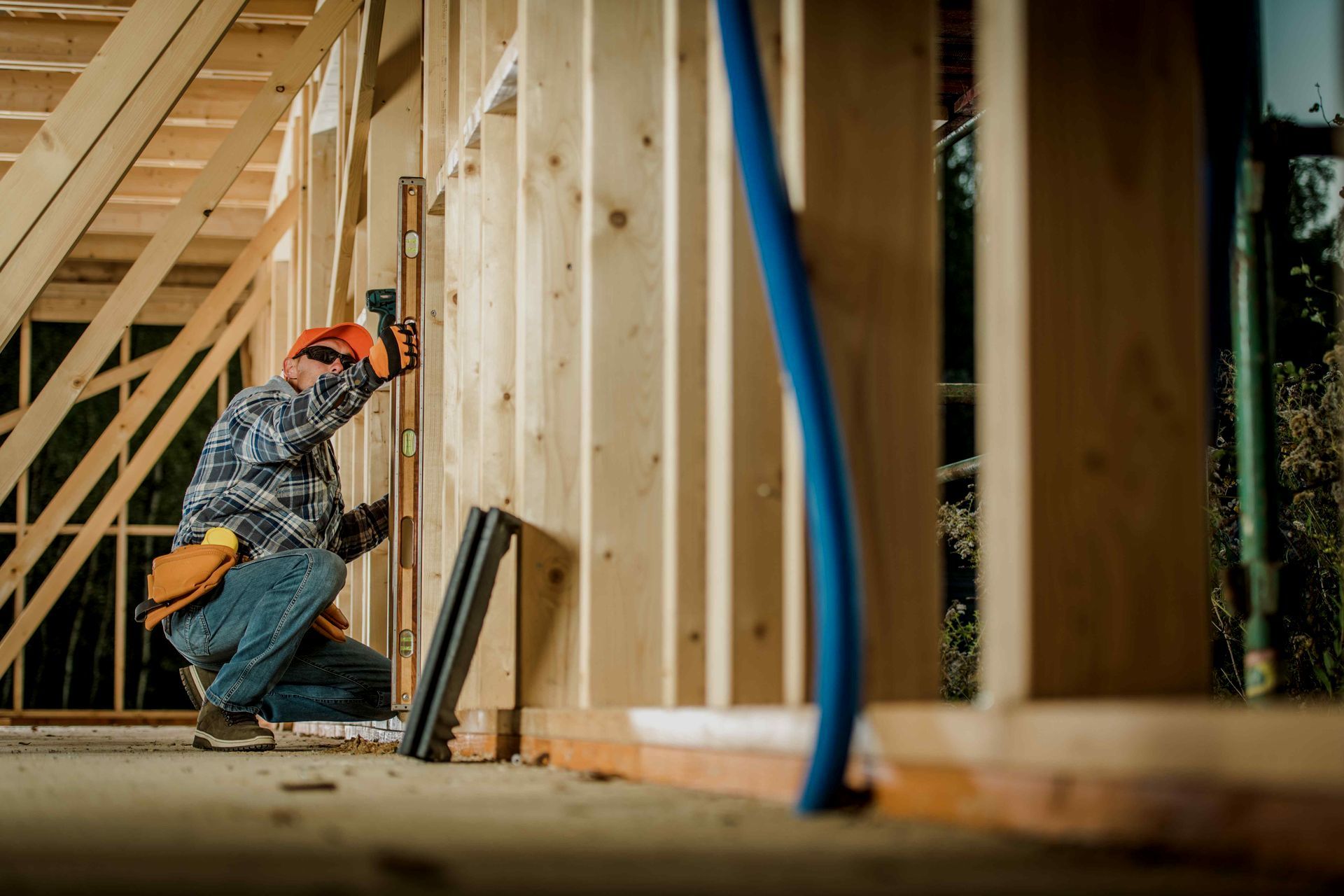 A construction worker is measuring a wall with a level.
