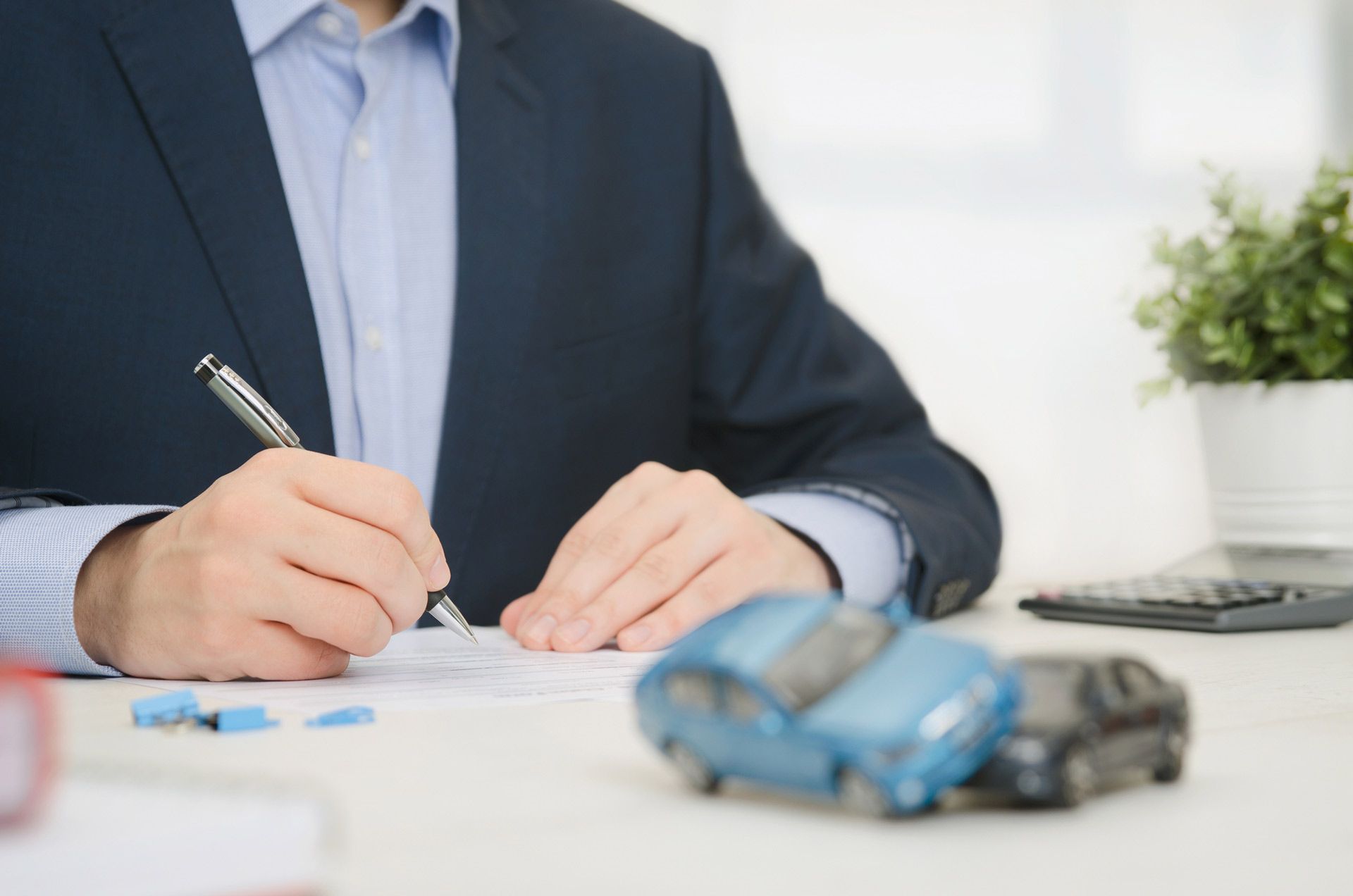 Insurance agent sits in an office with a document with a blurry pair of toy cars in front of it - Loganville, GA - Taurus Insurance