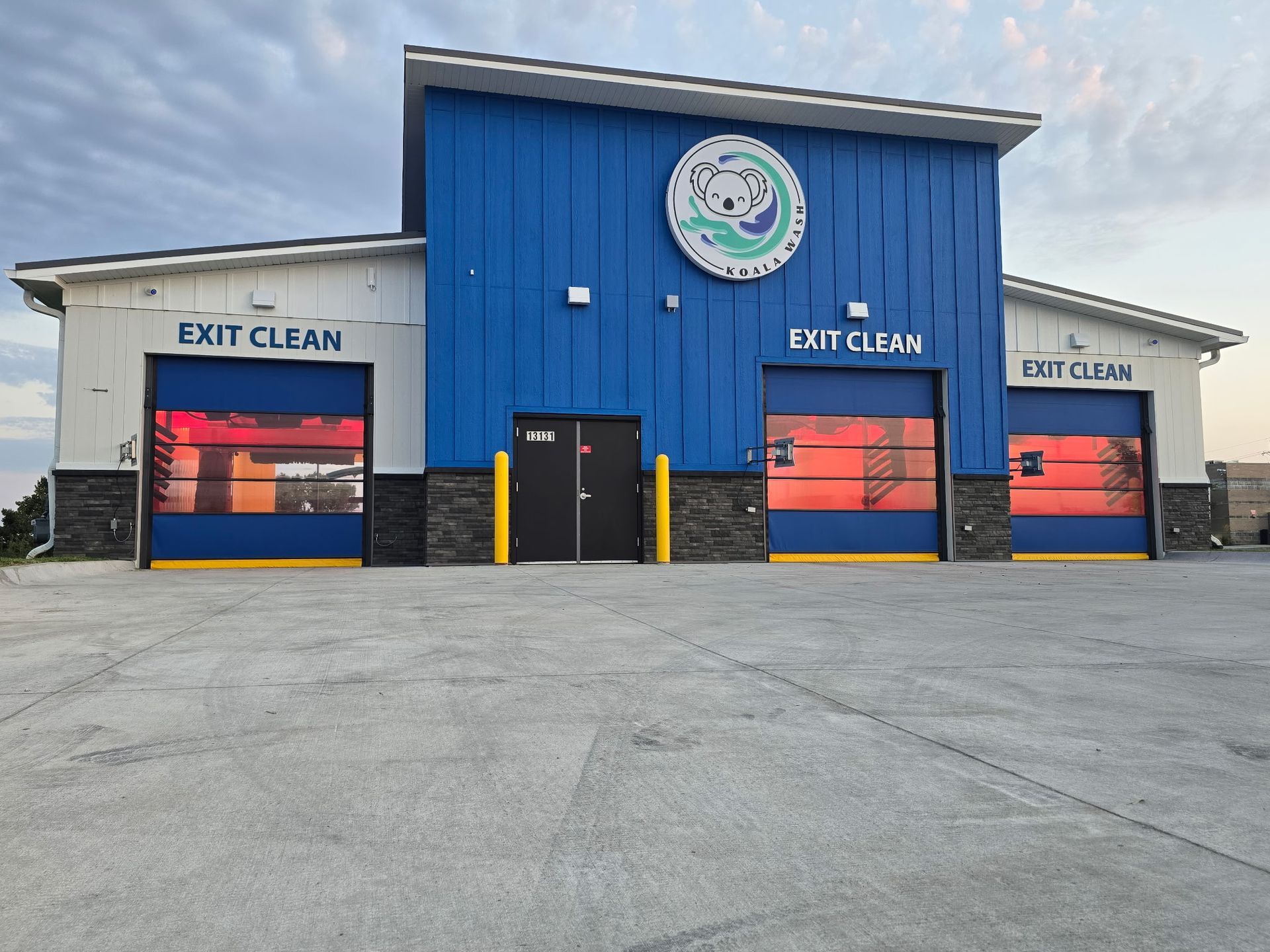 Blue auto detailing building with three garage bays, labeled Exit Clean and Spot Clean, viewed from the front.