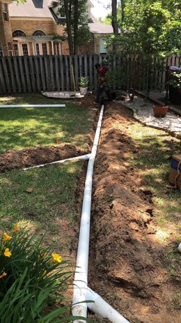 A drain pipe is being installed in a backyard.