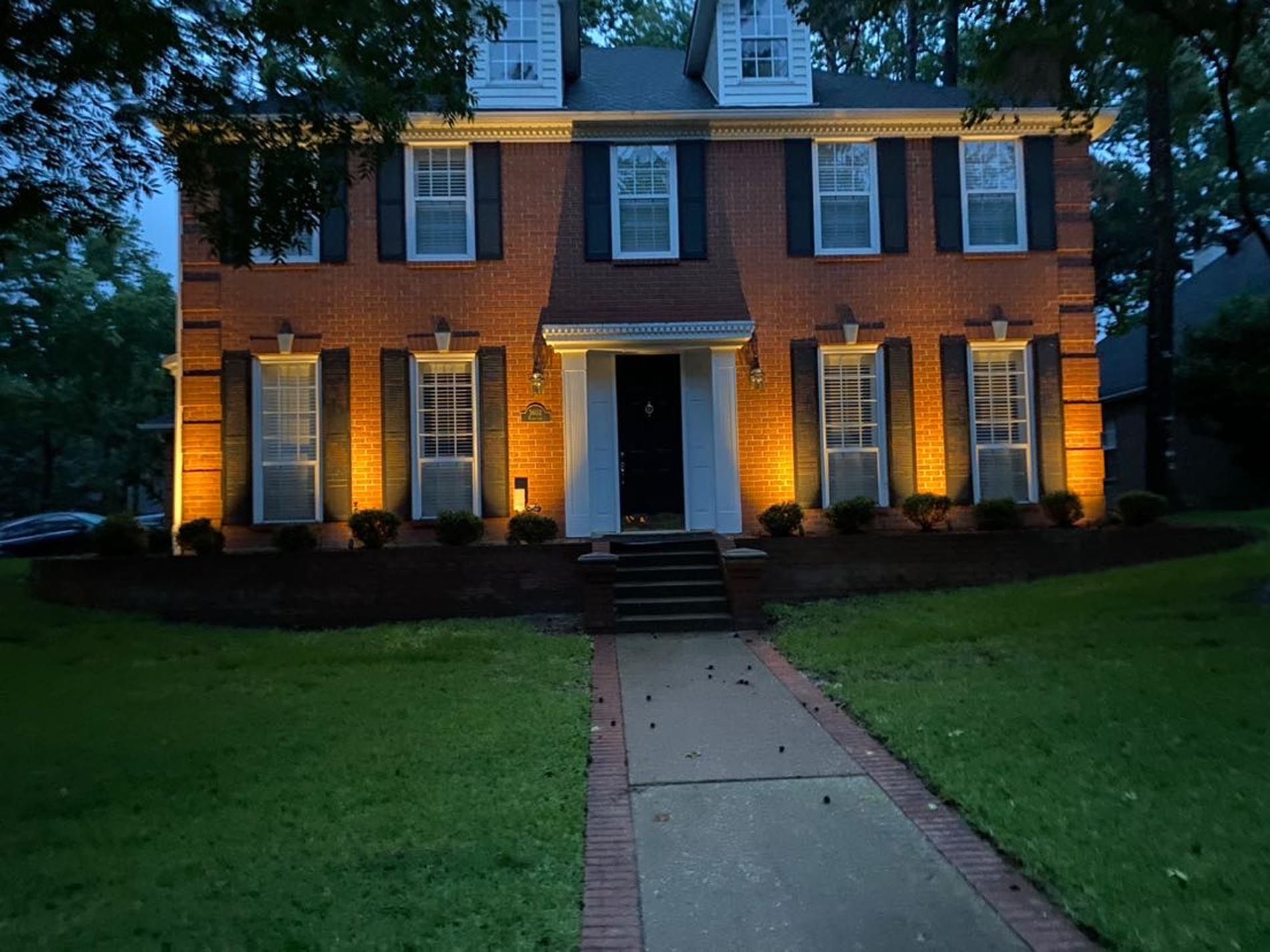 A large brick house is lit up at night