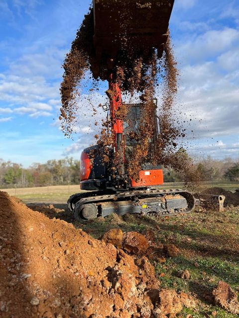 A bulldozer is digging a hole in the dirt in a field.