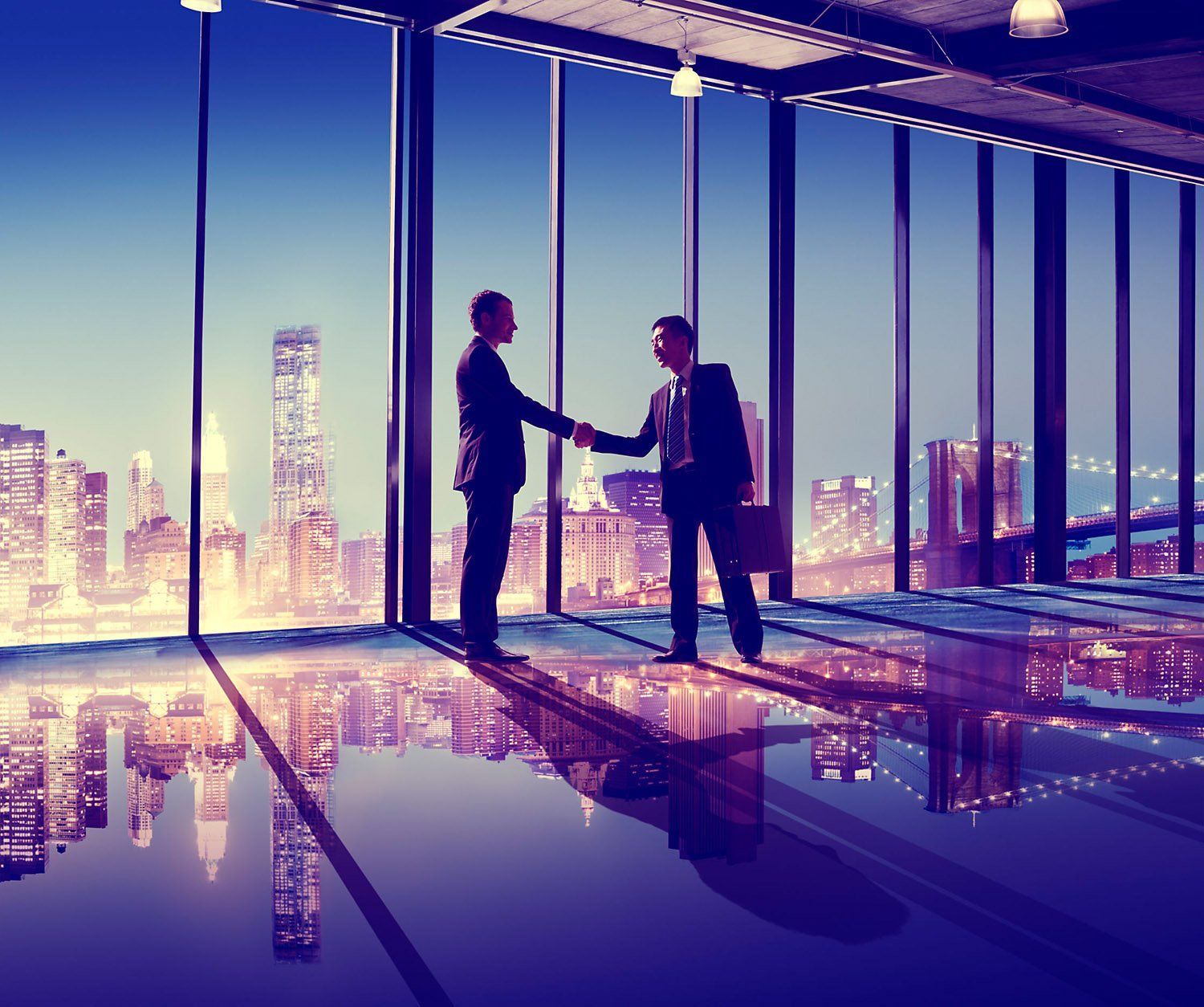 Two men are shaking hands in front of a window with a city skyline in the background.