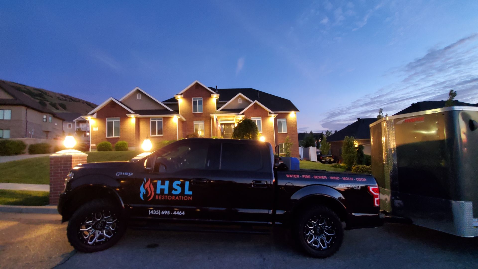 A hsl truck is parked in front of a house at night.