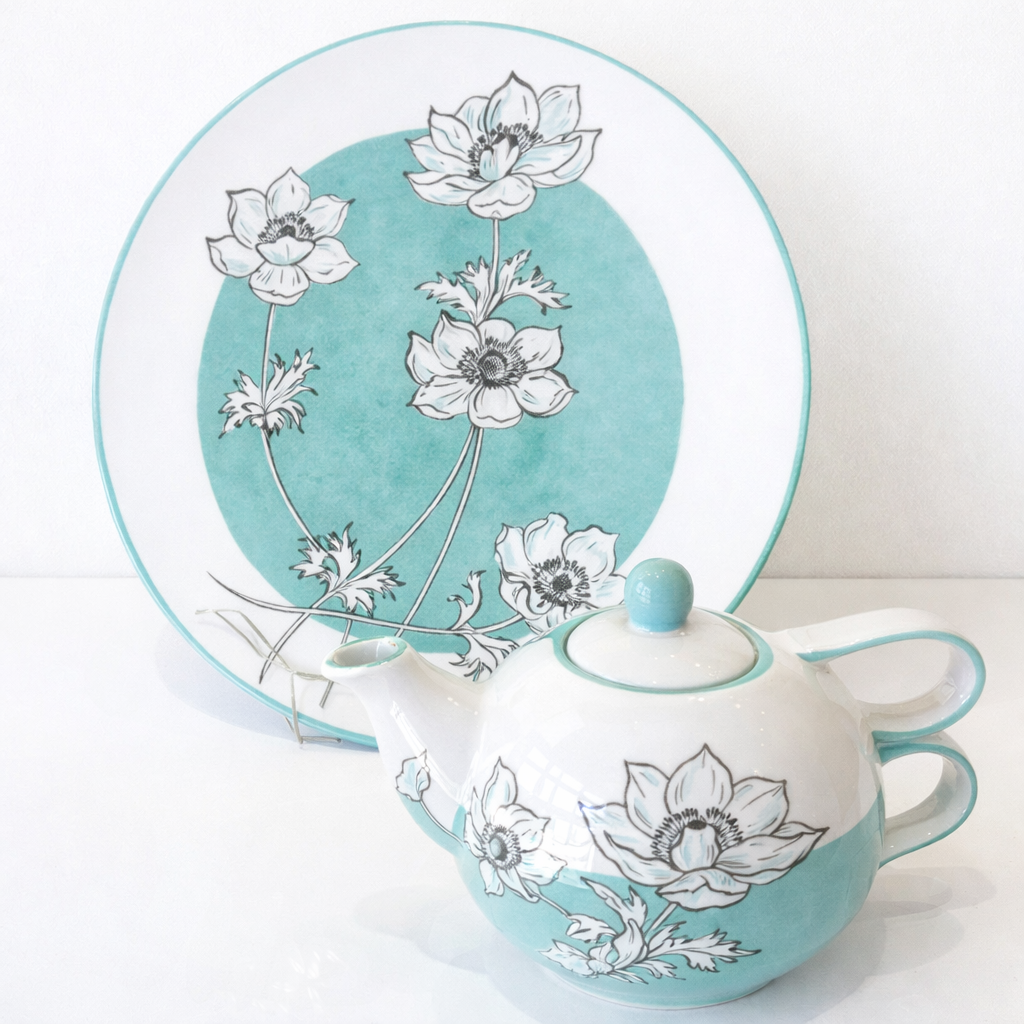 Piatto e teiera con motivo floreale verde acqua e bianco.