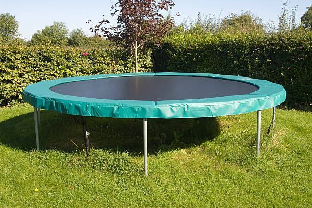 A trampoline with a green cover is sitting in the grass.