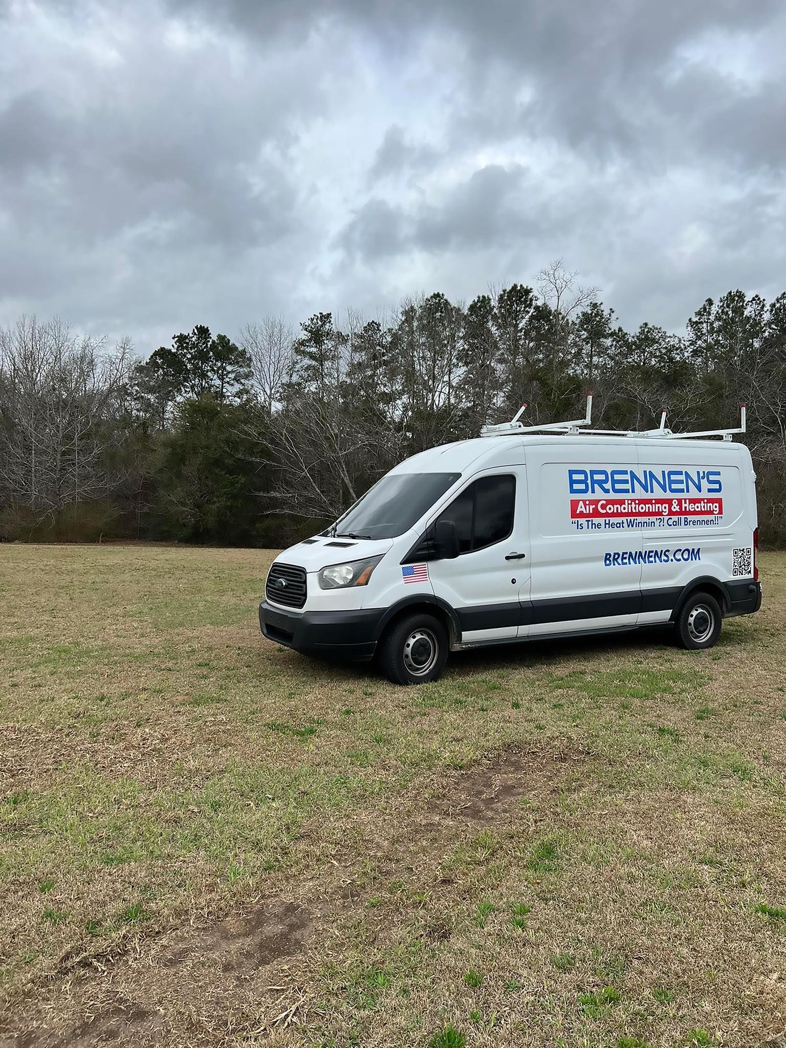 A white van is parked in a grassy field.