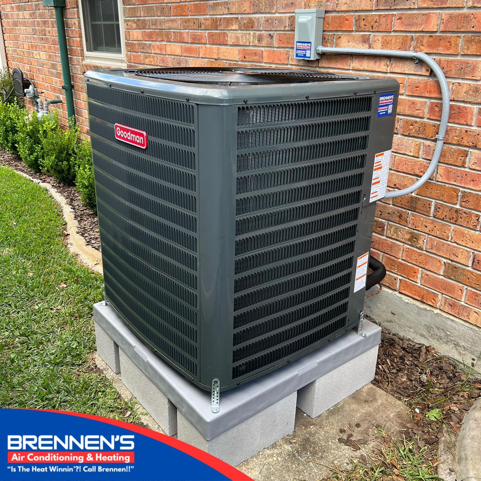 A large air conditioner is sitting on top of a brick wall.