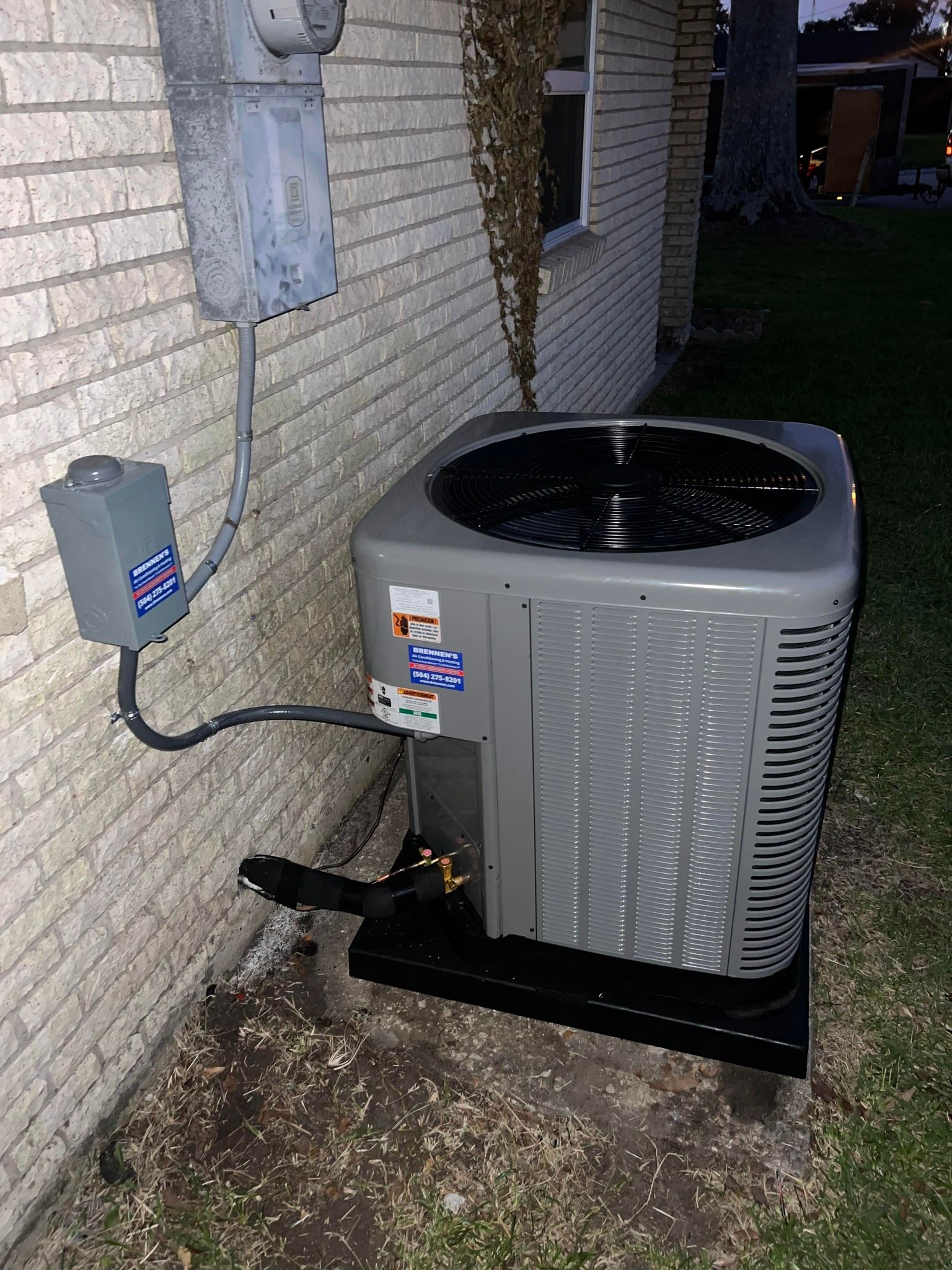 An air conditioner is sitting on the side of a brick building.