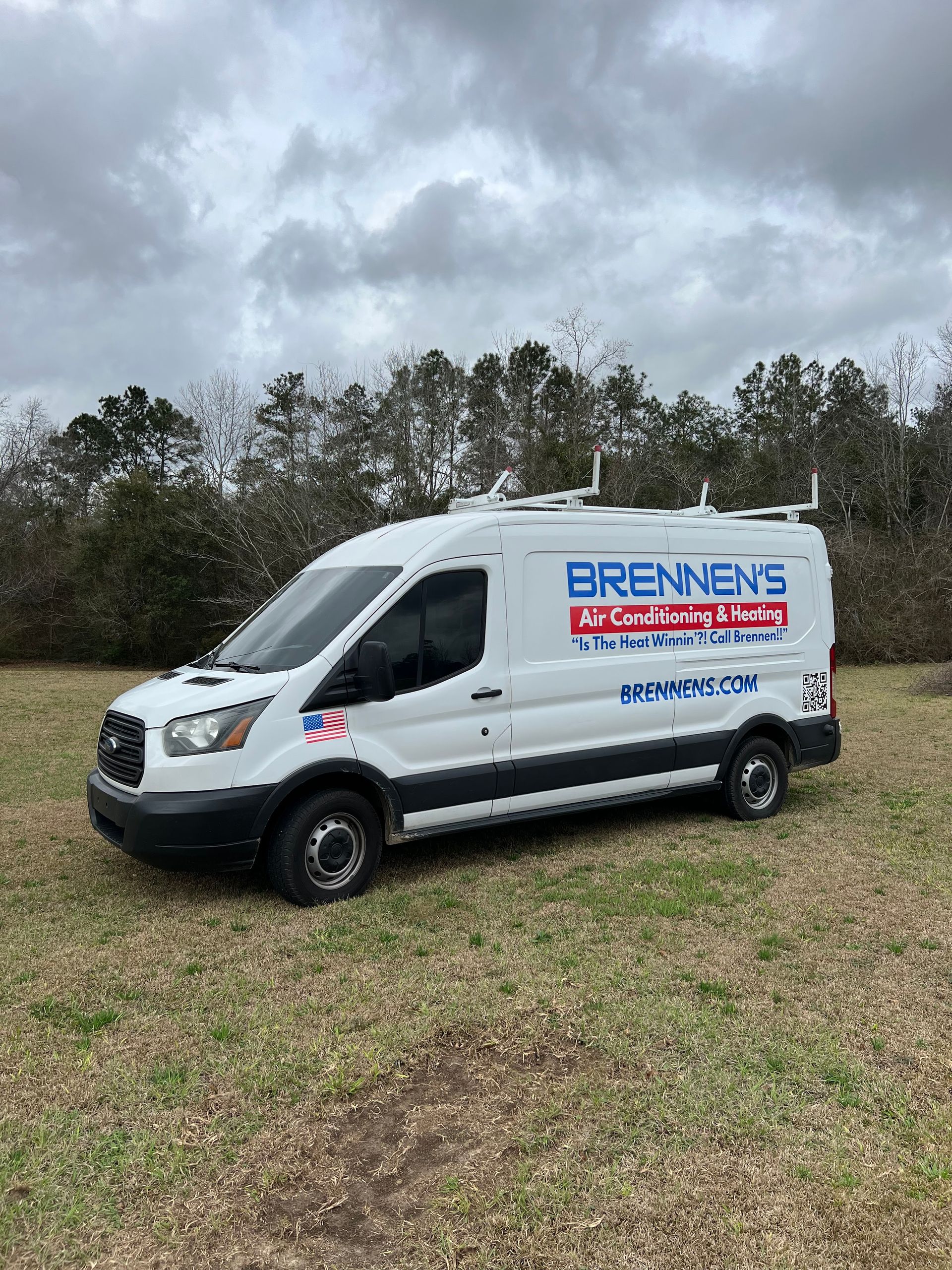 A white van is parked in a grassy field.