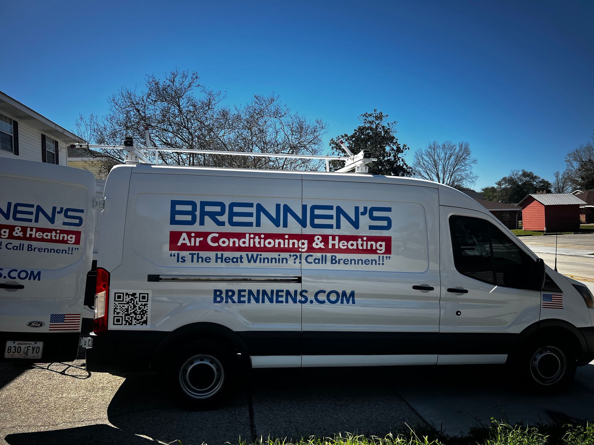 Two brennen 's air conditioning and heating vans are parked in a driveway.