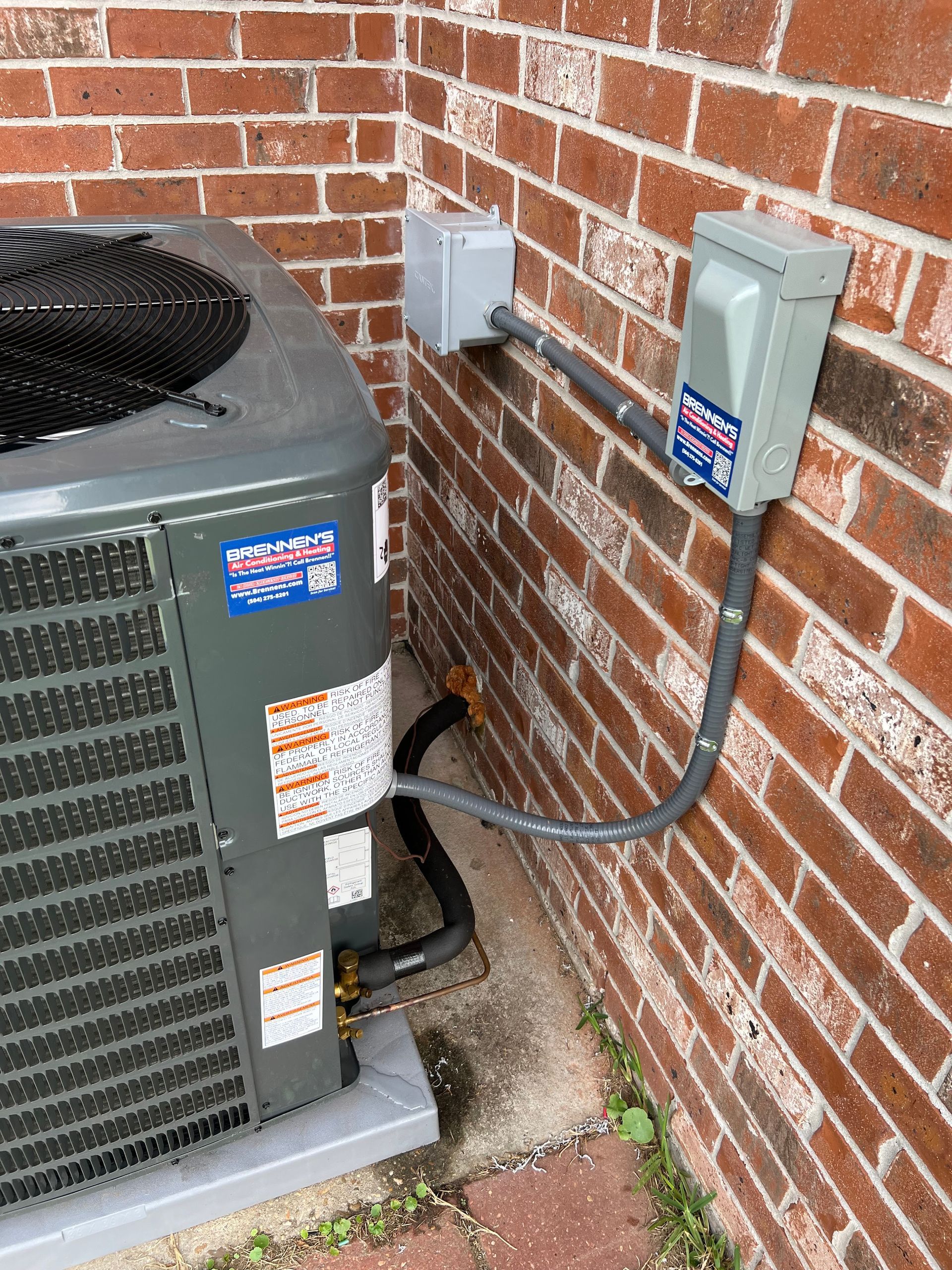 An air conditioner is connected to a brick wall.