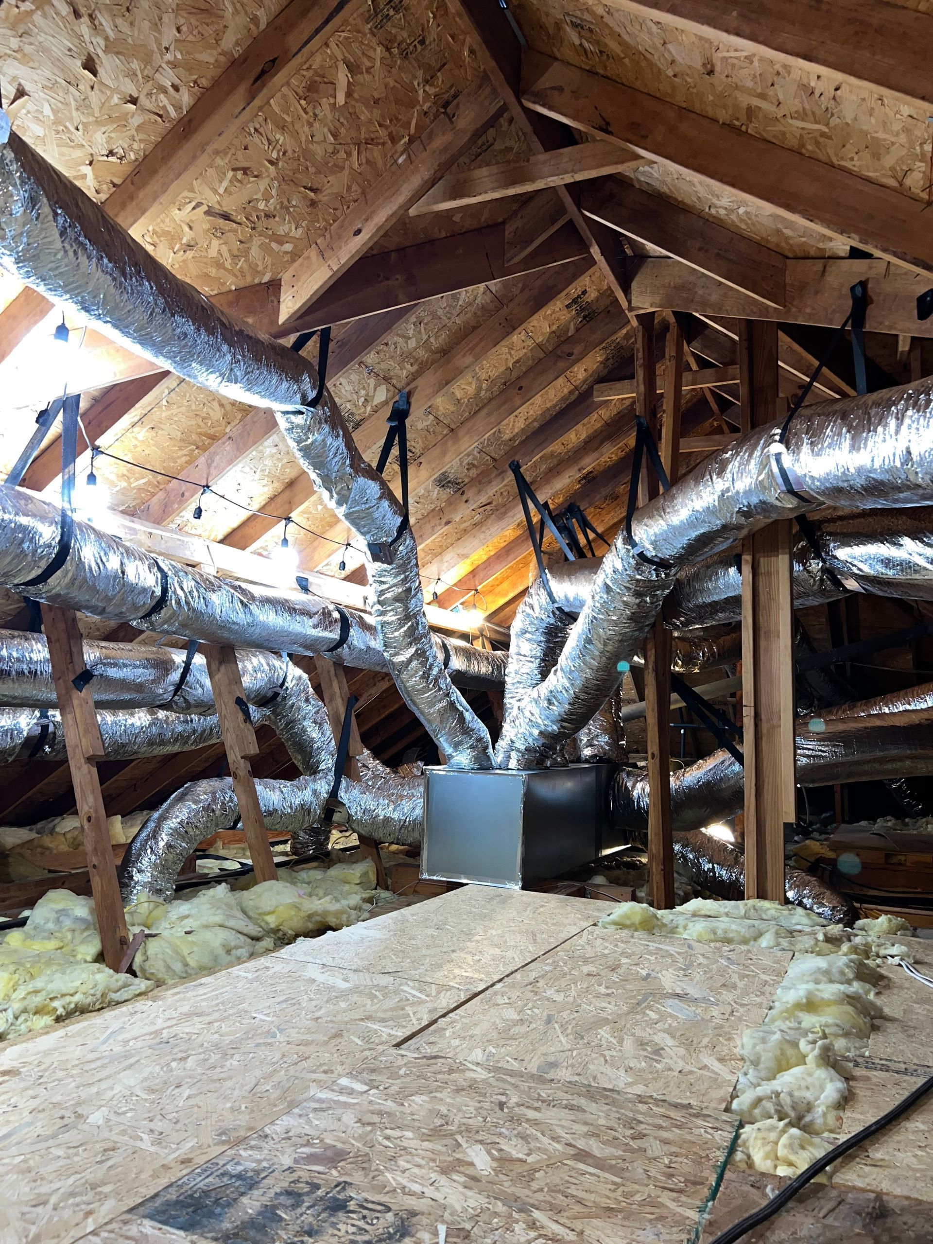 There are a lot of ducts in the attic of a house.