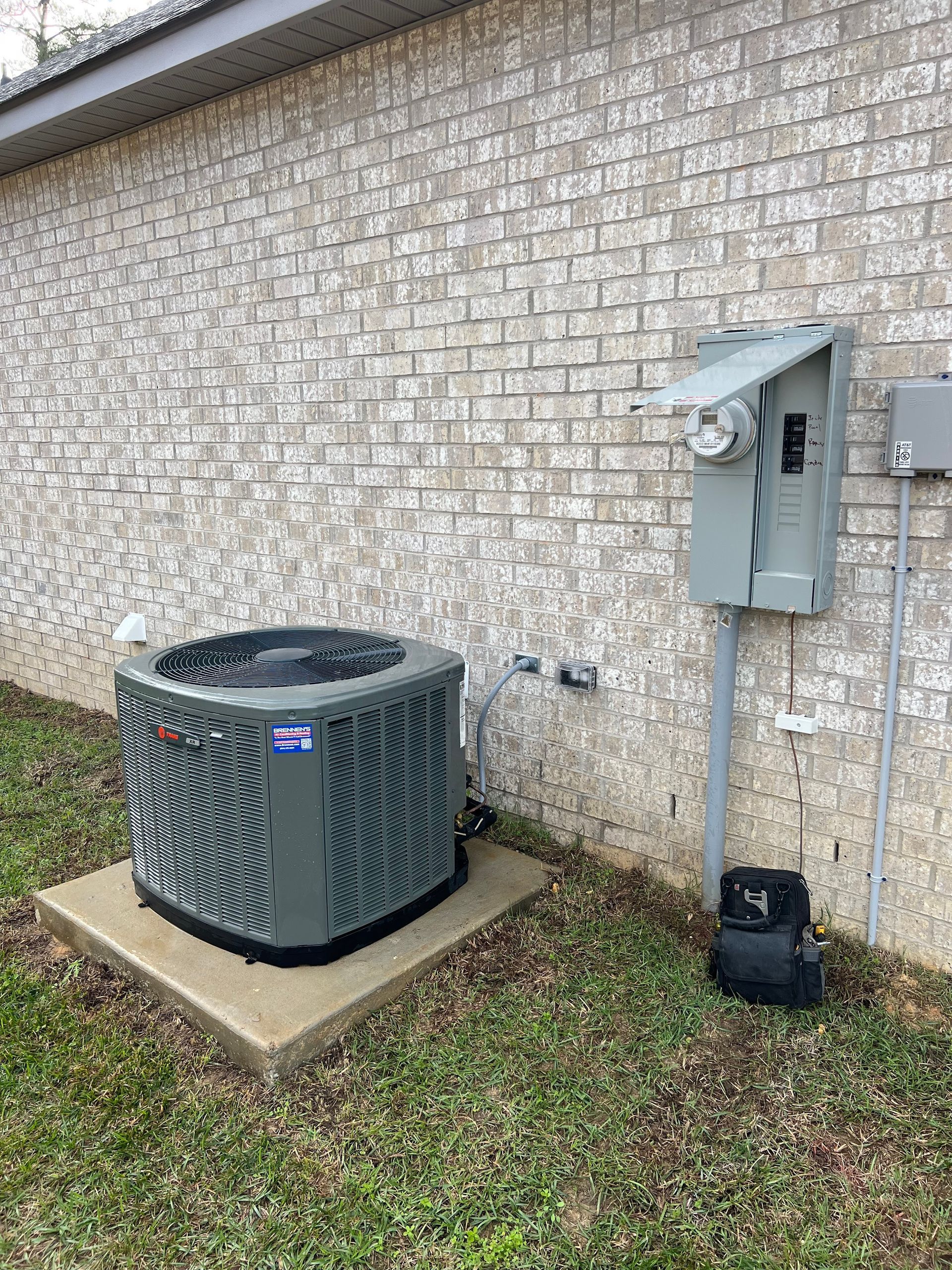 An air conditioner is sitting on the side of a brick building.