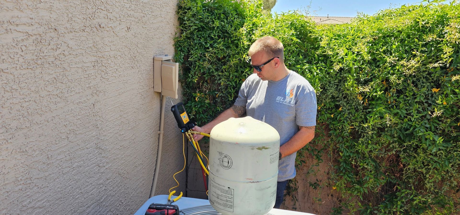 A man is working on a water heater outside of a building.