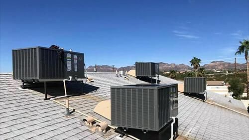 There are a lot of air conditioners on the roof of a building.