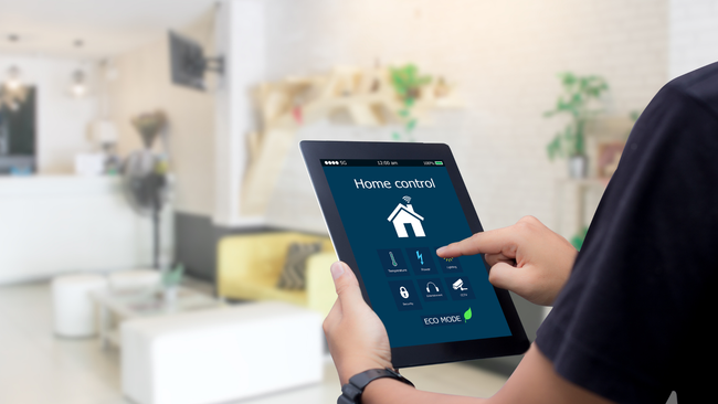 A person is holding a tablet in their hand in a living room.