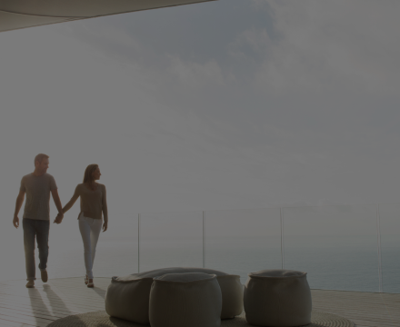 A man and a woman are walking on a balcony holding hands.