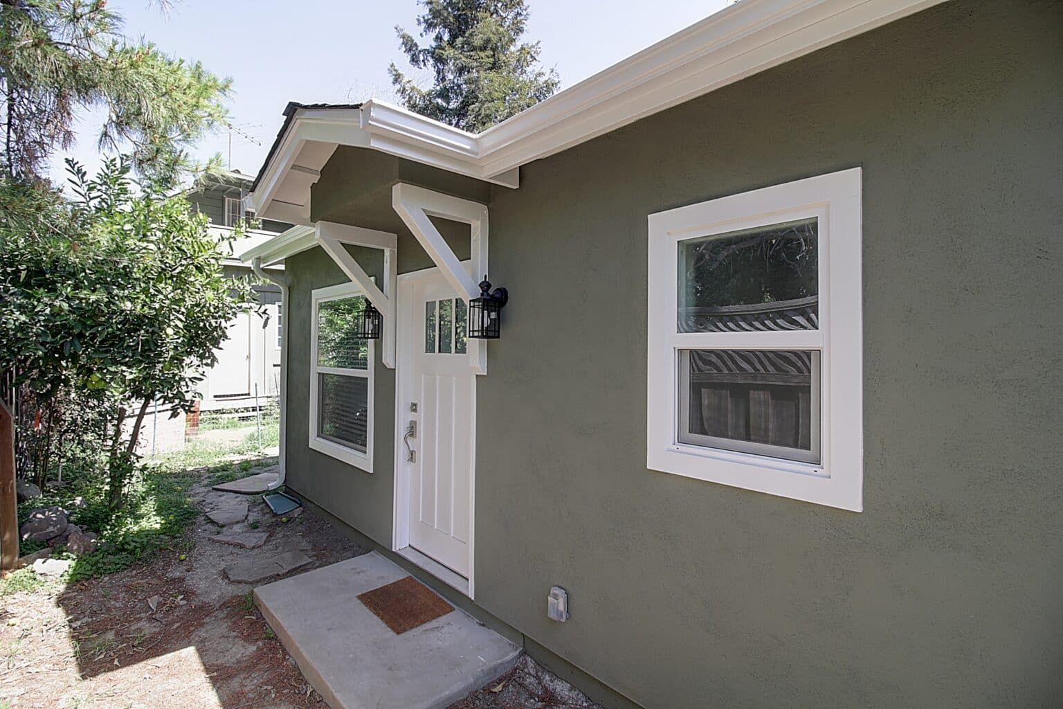 A green house with a white door and windows